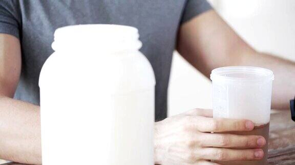 男人在健身跟踪器与罐子和瓶子准备蛋白质奶昔