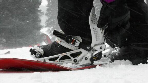 一个人把他或她的滑雪板扔到雪上的慢动作镜头把他们的靴子脚进入绑定剪绑定和滑雪板远离埃尔多拉滑雪度假村附近的博尔德科罗拉多州在一个下雪的阴天的冬天