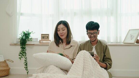 年轻的亚洲夫妇在客厅里谈笑风生