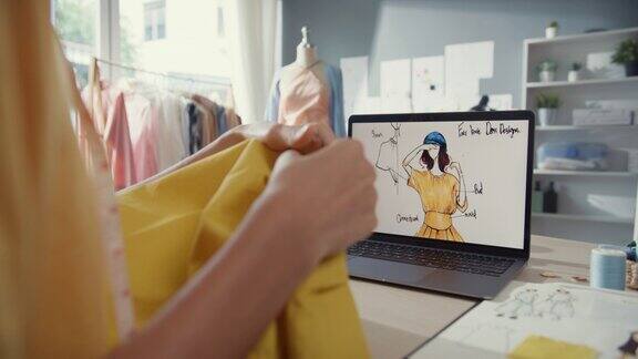 近距离年轻的亚洲女裁缝用笔记本电脑图形素描照片用卷尺测量织物比较样品在商店的桌子上创建服装设计新系列量身打造创业理念