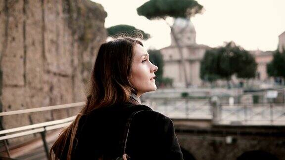 一名穿着黑色外套的女游客正走过罗马广场的桥女孩对意大利古罗马古城感到兴奋