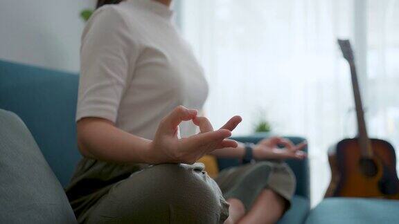 在家里客厅的沙发上女性双手握着瑜伽姿势冥想的特写镜头