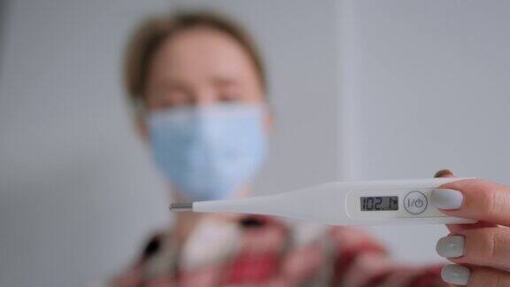 慢动作:女人戴着医用口罩在家看着医用温度计