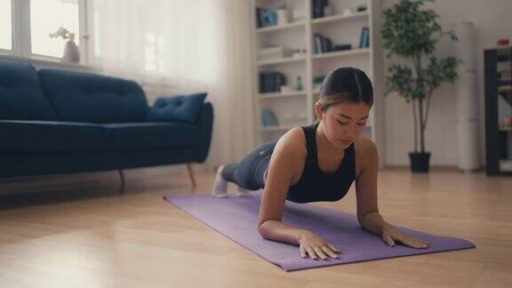 年轻美丽的亚洲女人趴在垫子上在家健身训练锻炼