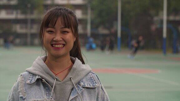 校园里年轻的亚洲女孩在镜头前微笑的肖像
