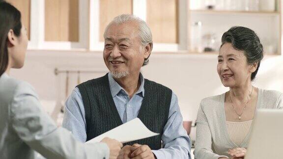年长的亚洲夫妇愉快地签署协议