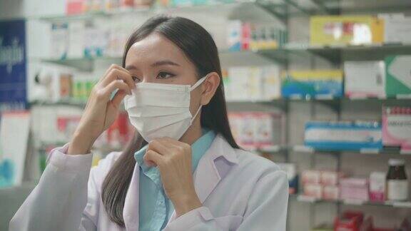 亚洲女性药剂师戴着外科口罩在现代药店的肖像covid-19和大流行