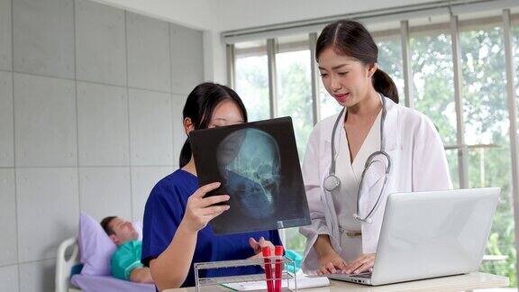 女医生和护士助理在病房里检查x光片并讨论病人的症状在手术前拿着并看着病人的脑部x光片