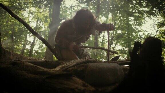 穿兽皮的原始穴居人用弓钻法生火的剪影尼安德特人点燃人类文明史上第一次人造火低角度拍摄