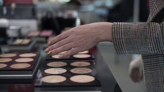 在化妆品商店里一名男性顾客选择粉底并在手上测试粉底以匹配她的肤色