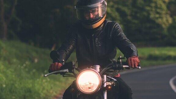日落时分骑着经典摩托车的男子在乡村公路上