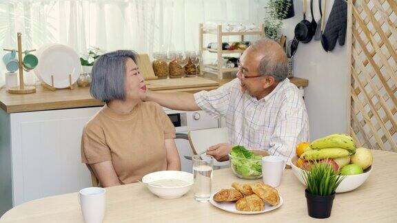 餐桌上亚洲老爷爷给老奶奶或老伴喂菜充满爱意