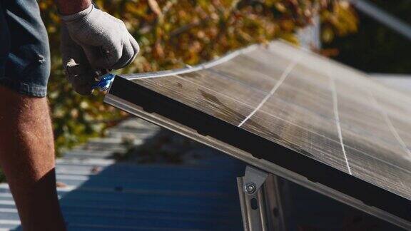 工人在金属支架上安装太阳能电池板(特写)房屋屋顶人工安装光伏太阳能板的近景工程师在户外工作