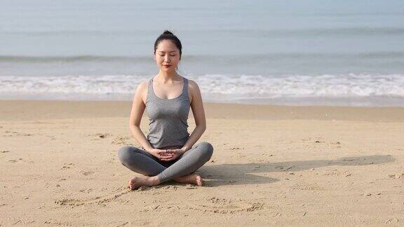 年轻的亚洲女人在海滩上做瑜伽