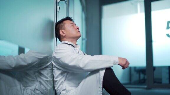 疲惫不堪的医生坐在医院室内的走廊里