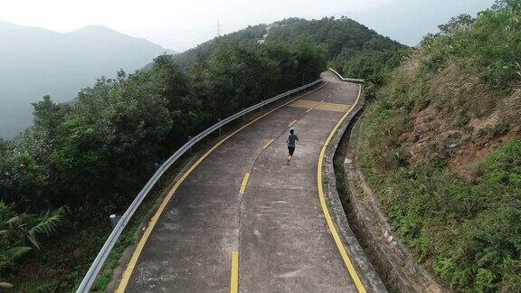 空中拍摄的健身女跑步者在山顶的小道上跑步