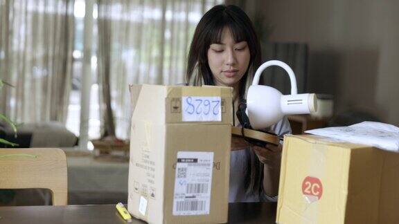 年轻的亚洲女人从网上购物开箱产品