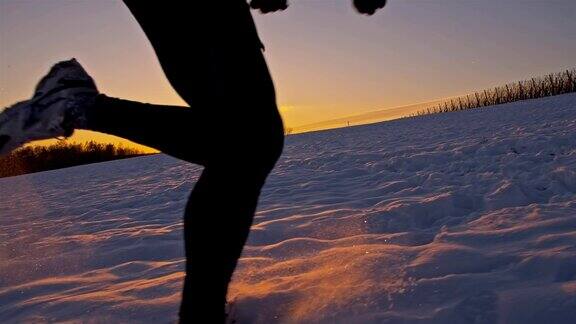 SLOMO慢跑者在夕阳下的雪中跋涉