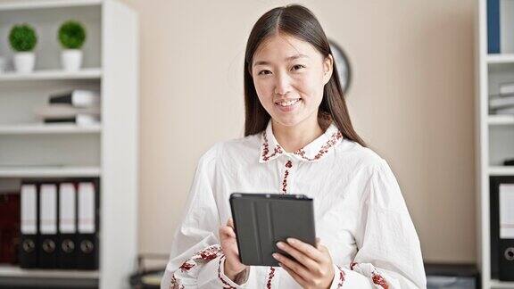 年轻的中国女商务工作者在办公室用触控板微笑