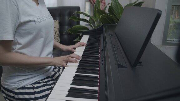 特写亚洲少年在家里的客厅里弹奏键盘钢琴美丽的女孩钢琴家在社交媒体上直播弹钢琴网络影响者Vlog或网络教学