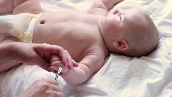 婴儿睡觉时妈妈用剪刀给他剪指甲护理一个孩子剪裁如何成功修剪新生儿的指甲妈妈给小孩剪指甲卫生的婴儿