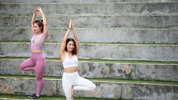 2个亚洲华人女性朋友在公共公园晨练瑜伽冥想