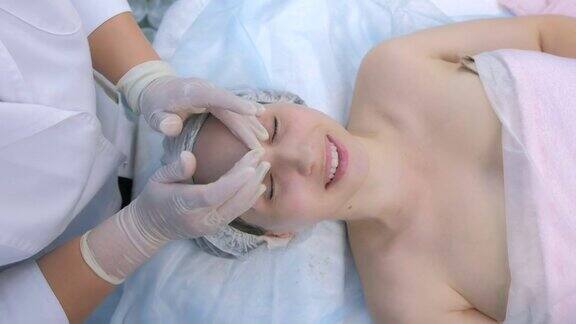 美容师戴着手套在病人脸上涂抹护肤霜按摩皮肤