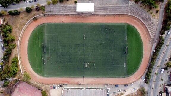 一架无人机从空中拍摄孩子们在足球场踢足球的俯视图