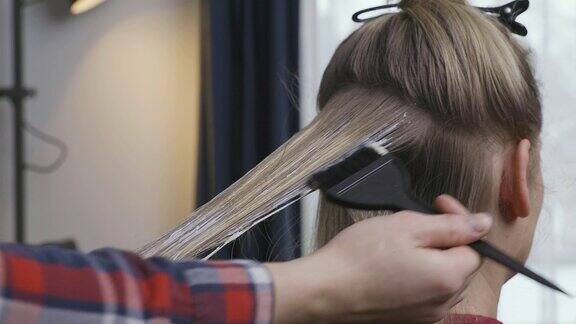女人在家里用刷子把头发染成一个金发女人呆在家里