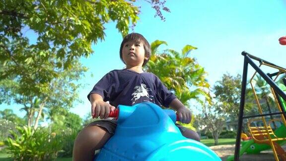 小男孩在操场上骑着蓝色的飞机玩具