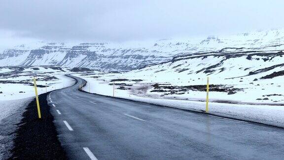 平移拍摄:道路延伸冰岛冬季景观雪山