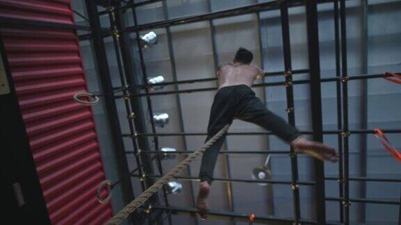 下面直接低角度视图极限运动亚洲华人男子运动员攀登绳在健身房