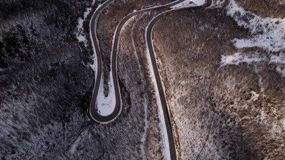 高角度鸟瞰无人机跟随汽车在弯弯曲曲的道路上槽的树木在山脉与白色的雪在冬天的一天在塞尔维亚克纳兹瓦茨附近-旅行旅行度假概念
