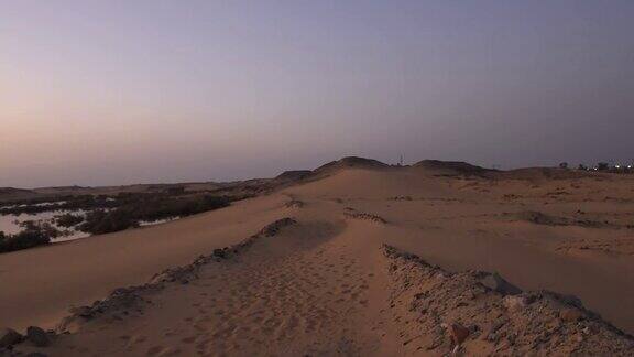在日落时分走在沙丘上摄像机沿着沙漠中的大沙丘移动