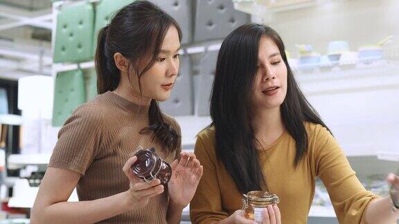 年轻的成年亚洲女性和朋友喜欢在大卖场购物一位女士推着购物车在超市寻找家用产品