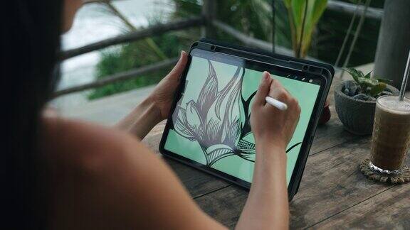 女插画家在咖啡馆的平板电脑上画着海景棕榈树在海边露台上工作的自由职业者漂亮女人喝卡布奇诺特写后视图