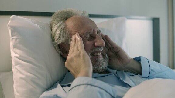 老年病男患有偏头痛在床上按摩太阳穴神经衰弱