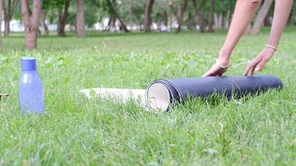 一个女孩在公园里展开瑜伽垫练习瑜伽