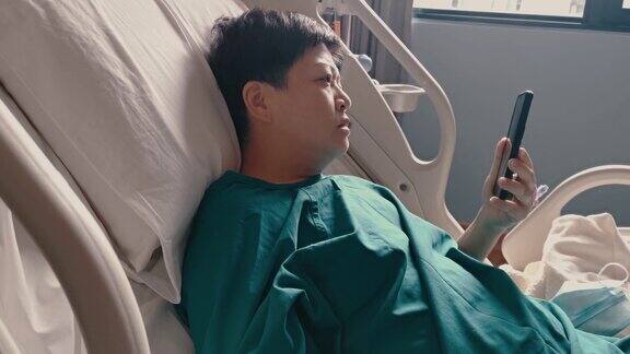 一名亚裔华人女病人躺在医院病房的病床上正在进行视频通话