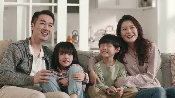 年轻的亚洲家庭在家里一起看电视