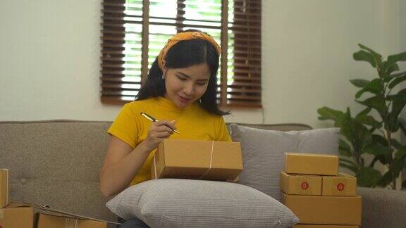 启动中小企业亚洲妇女与包装盒工作而坐在沙发上