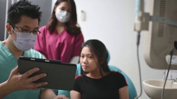 亚洲华裔男性牙医向病人解释牙齿x光片