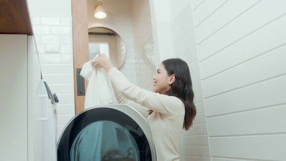 快乐的亚洲年轻女子正在家里洗衣服