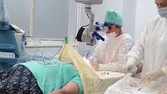两位女外科医生用显微镜和医疗器械进行眼科手术