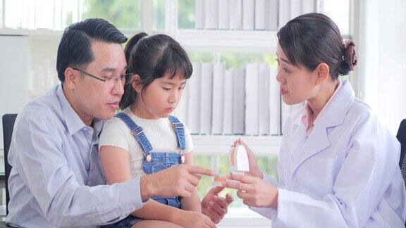 医学、牙科和保健概念-牙医在牙科诊所向儿童病人和她的父亲展示牙齿模型中国和香港的医疗系统