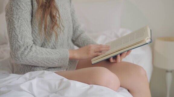 年轻女子在家里的床上看书