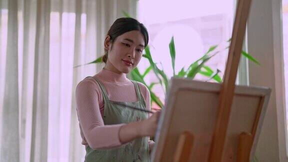 亚洲女艺术家在她的艺术工作室里用画笔在画布上作画和使用不同的丙烯酸颜料艺术家的创作理念