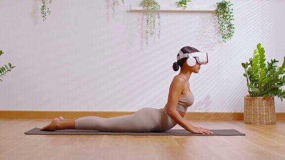 亚洲女子使用虚拟现实眼镜练习瑜伽眼镜蛇姿势锻炼Metaverse在线社区她自己在Metaverse用未来数字技术虚拟现实练习瑜伽健康培训班