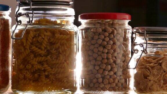滑动玻璃罐装满豆类从一个架子在食品储藏室