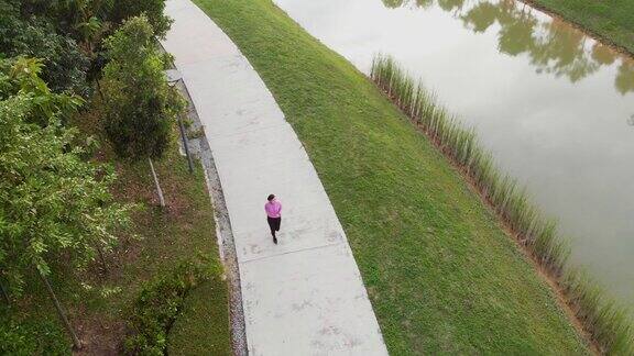 运动的年轻亚洲女人在公共公园跑步